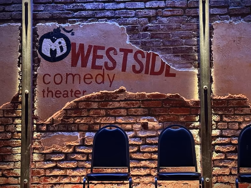 Westside Comedy Show Stage A brick comedy club background with the WestSide Comedy logo on it